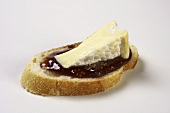 Slice of cheese with raspberry preserves on a slice of baguette
