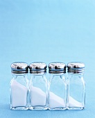 Four Glass Salt Shakers with Varying Amounts of Salt
