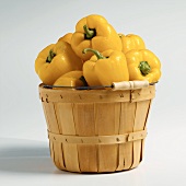Wooden Market Basket Filled with Yellow Bell Peppers on White Background