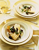 White Fish Fillets Topped with Morel Mushrooms and Fiddle Heads on Plates; Flatware