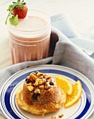 Walnut Raisin Sweet Roll on a Plate with Orange Slices; Strawberry Milkshake
