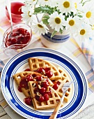 Plate of Waffles Topped with Cherry Sauce; Fork; Pitcher of Cherry Sauce with Spoon; Daisies