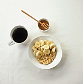 Muesli with bananas, honey and cup of black coffee