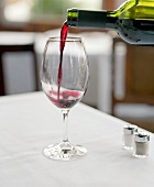 Pouring red wine from a bottle into a glass