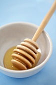 Honey dipper with honey in a white bowl