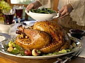 Stuffed turkey on table, woman serving green beans (USA)