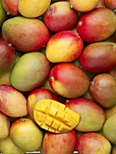 Many whole mangos and one cut into cubes (full-frame)