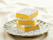 Three Lemon Bars Topped with Powdered Sugar Stacked on a Plate