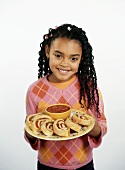 Young Girl Holding a Plate with Slices of Stromboli and a Bowl of Marinara Sauce