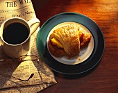 Croissant mit Schinken und Ei, Kaffee, Zeitung