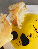 Weißbrot auf Teller mit Olivenöl und Tropfen Balsamicoessig