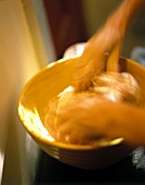Hands kneading dough in a bowl