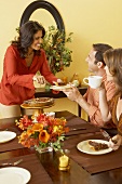 Woman Standing Serving Pie to Man at Thanksgiving Table, Woman Drinking Coffee and Eating Pie