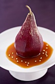 Poached pear sprinkled with gold dust in caramel sauce