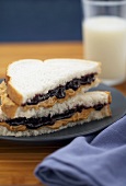 Peanut Butter and Jelly Sandwich Cut in Half and Stacked on Plate, Glass of Milk