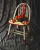 Freshly Washed Tomatoes in and Around a Colander on a Chair; Sliced Tomato with Salt and Knife