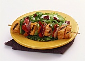 A Chicken Kabob with Bell Peppers and Onions Over Salad