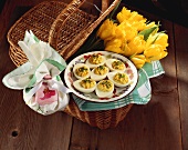 Gefüllte Eier und gelber Tulpenstrauss im Picknickkorb