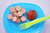 Sliced Hot Dog with Ketchup and a Plastic Fork on Blue Plastic Plate