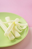 Three Sticks of String Cheese on a Plate, One Peeled