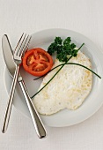 Egg White Omelet on a Plate with Fork and Knife and a Tomato