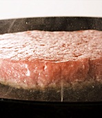 A burger being fried in a pan