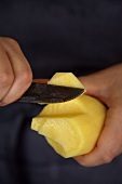 Stück von geschälter Kartoffel abschneiden