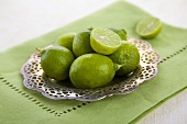 Whole and Halved Key Limes on a Metal Dish