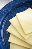 Mehrere Scheiben White American Cheese auf blauem Teller