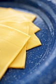 Mehrere Scheiben Yellow American Cheese auf blauem Teller