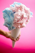 Hand Holding Blue and Pink Cotton Candy; Pink Background