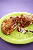 Partially Eaten Pepperoni and Mozzarella Calzone on a Green Plate