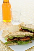 BLT Sandwich with Guacamole Halved on a Plate with Chips