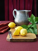 Fresh Lemons on a Cutting Board with a Knife; Pitcher