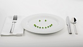 Place Setting with Peas Forming a Smiley Face on White Plate