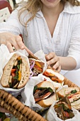 Frau greift nach Sandwich im Picknickkorb
