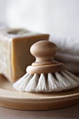 Spülbürste aus Holz, dahinter ein Stück Seife
