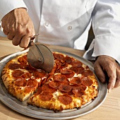 Chef Cutting Pepperoni Pizza with Pizza Cutter
