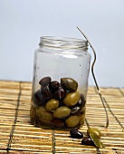 Eingelegte Oliven in einem Einmachglas auf einer Bambusmatte