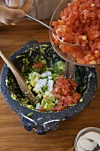 Adding Fresh Chopped Tomato to a Bowl for Guacamole
