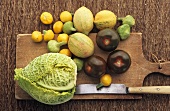 Verschiedene Früchte, Gemüse und Messer auf Schneidebrett
