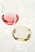 Zwei Gläser mit Weißwein und Rose und ein leeres Glas