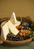 Käse mit Früchten und Mandeln in Holzschale