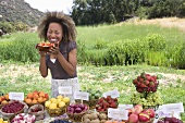Woman Smelling Organic Fruit at an Outdoor Market