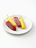 Red and Yellow Popsicles on a White Plate; White Background 