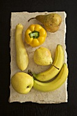 Gelbe Früchte und Gemüse auf einer Steinplatte