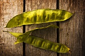 Three Pea Pods on Rustic Wooden Table