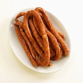 Long Links of Uncooked Chorizo on a White Plate; White Background