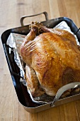 Whole roast turkey in roasting tin