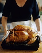 Woman Placing Roasted Turkey on Counter
